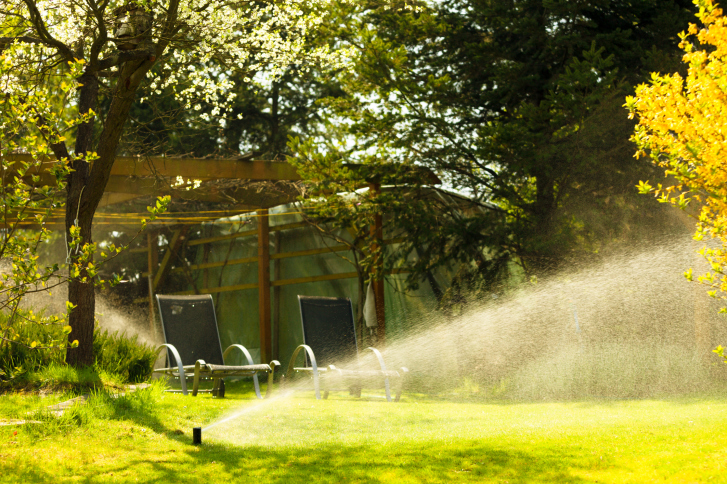 Gardening. Lawn sprinkler spraying water over grass.